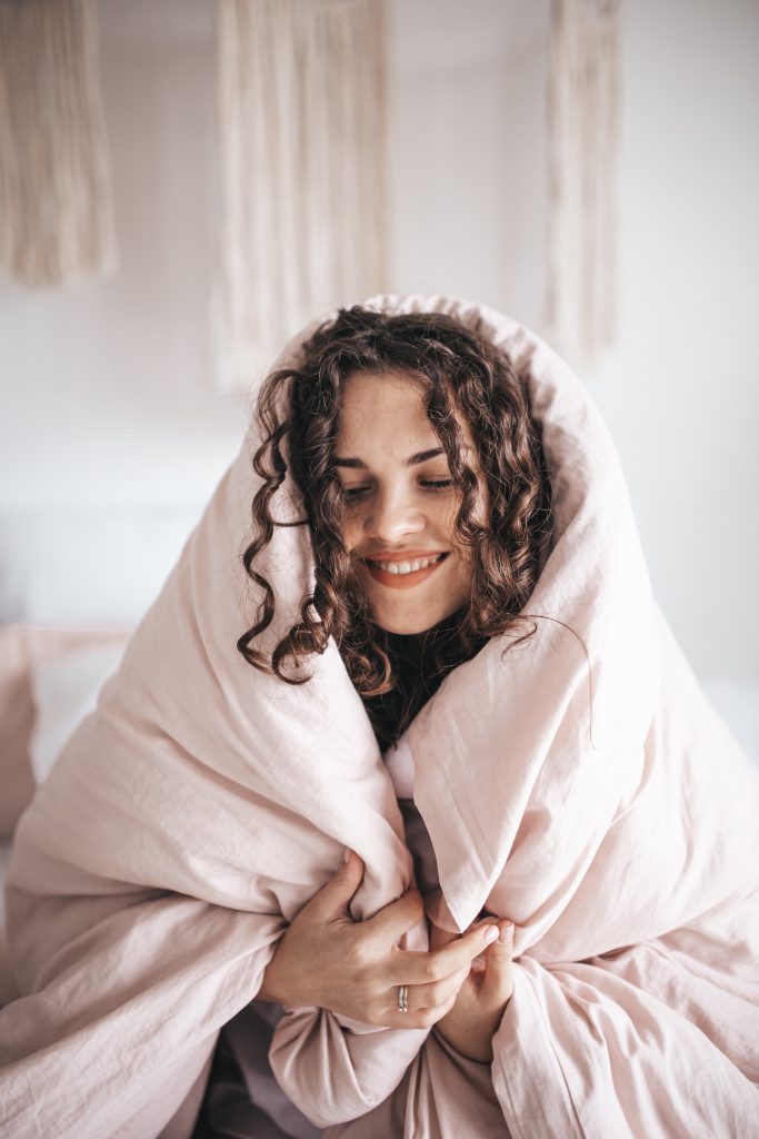 smiling woman wrapped in gray blanket